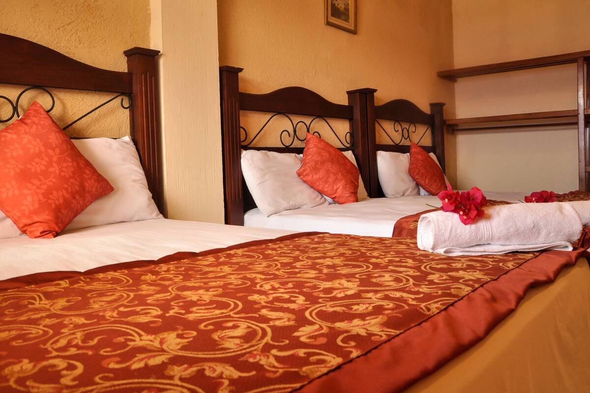 A hotel room with two beds, each with a wooden headboard and white linens.