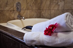 Un baño con lavamanos, una toalla y una flor roja.