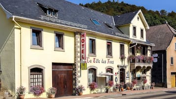 Un edificio amarillo con un letrero que dice "HOTEL La Tête des Faux" y "Restaurante".