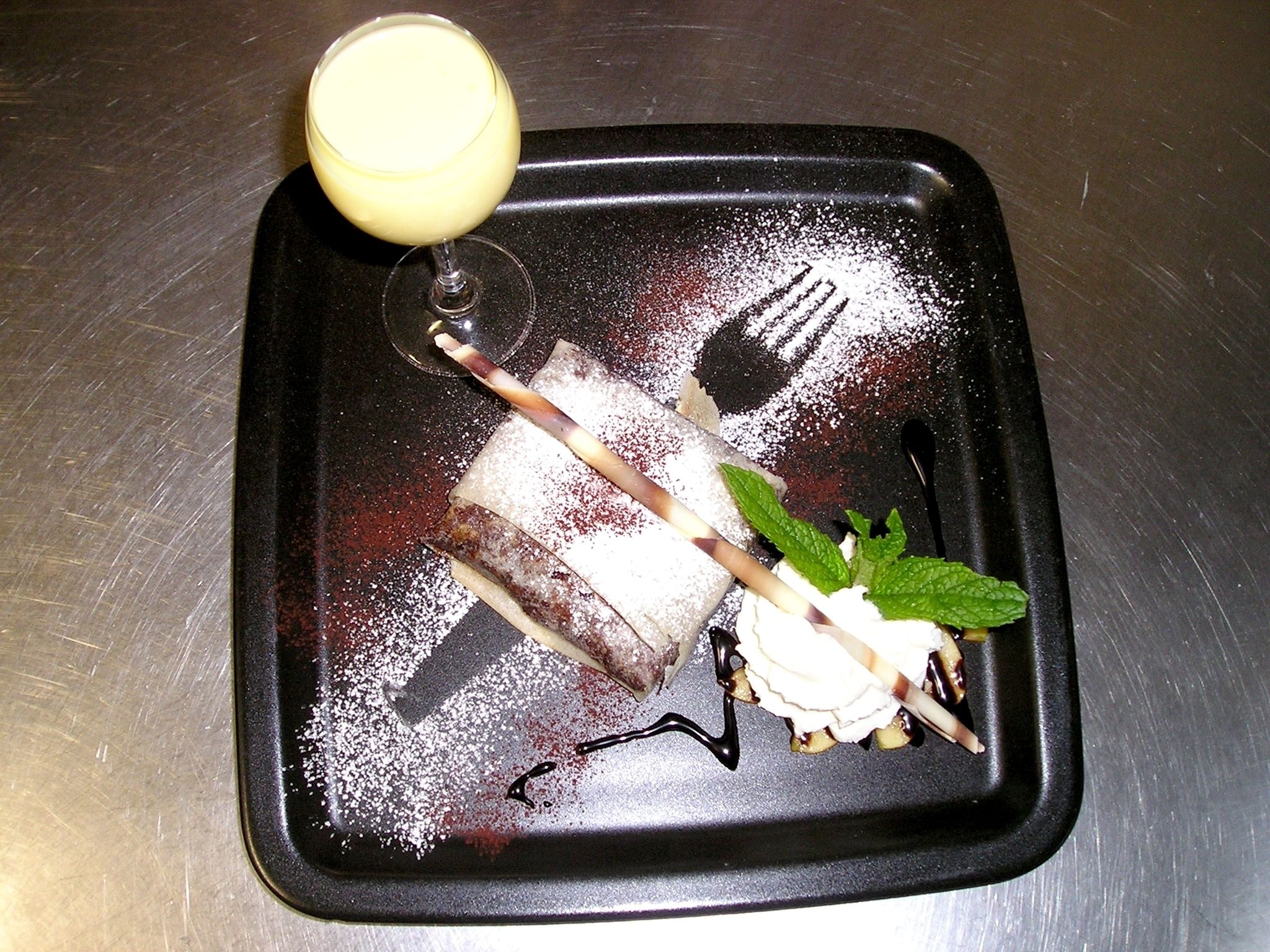 A dessert tray with a chocolate-covered cake, a scoop of ice cream, and a mint garnish.
