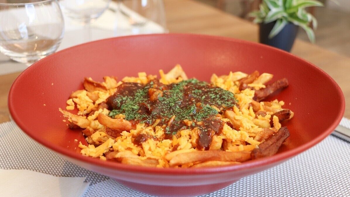 Een schaal eten met rijst, vlees en saus, op een tafel met placemat.