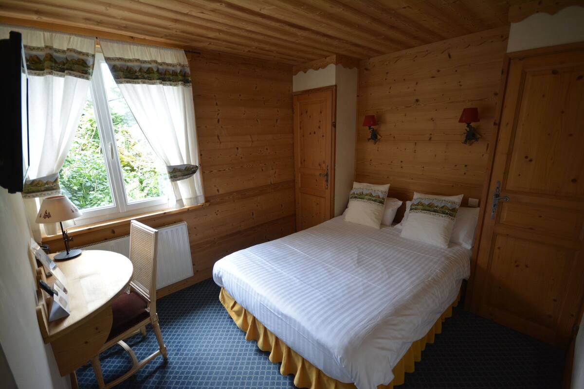 Une pièce en bois avec un lit, un bureau et une chaise.
