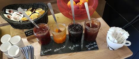 A table with various jams and a basket of fruits.