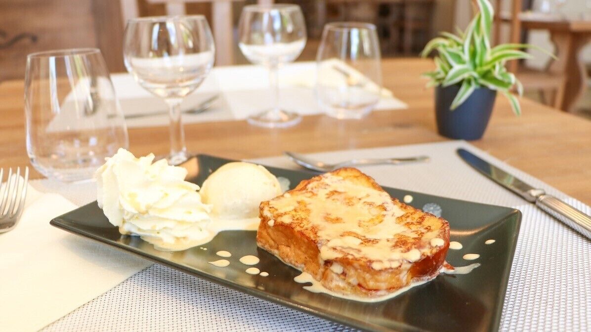 Un plato de postre con una rebanada de pastel y una bola de helado sobre un plato negro.