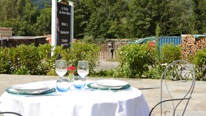 A table set outdoors with a mountain view, a sign indicating a restaurant, and a building with a sign in the background. - Logis Hôtel le Relais du Mont Blanc (Magland)