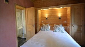 A wooden cabin bedroom with a bed, two pillows, a nightstand, and a wooden ceiling. - Logis Hôtel le Relais du Mont Blanc (Magland)