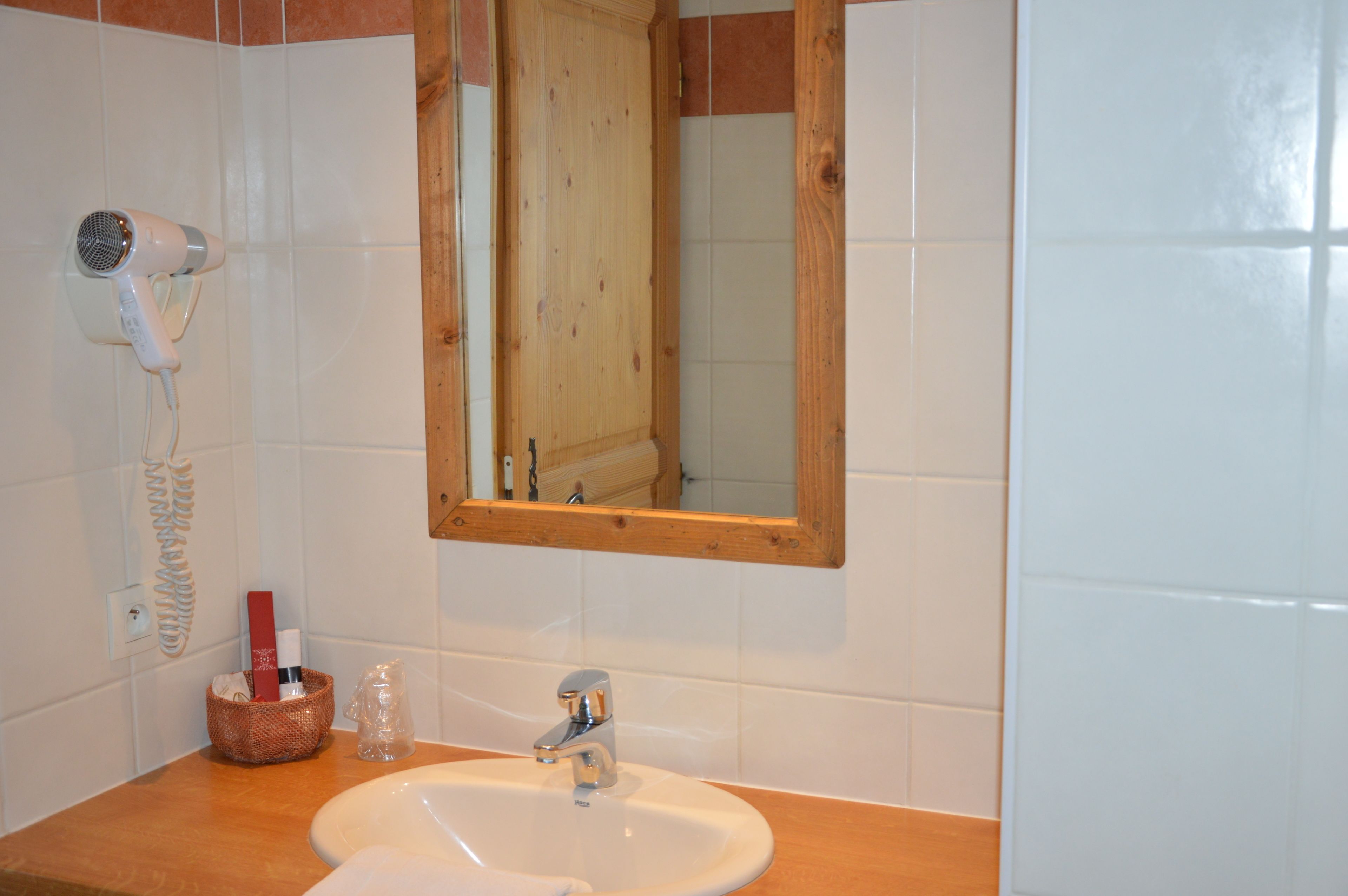 Un bagno con lavandino bianco, mobiletto in legno e specchio con cornice in legno.