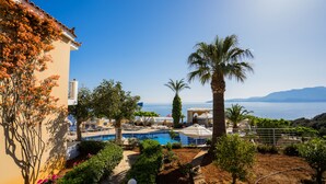 A resort with a pool, palm trees, and a view of the sea.