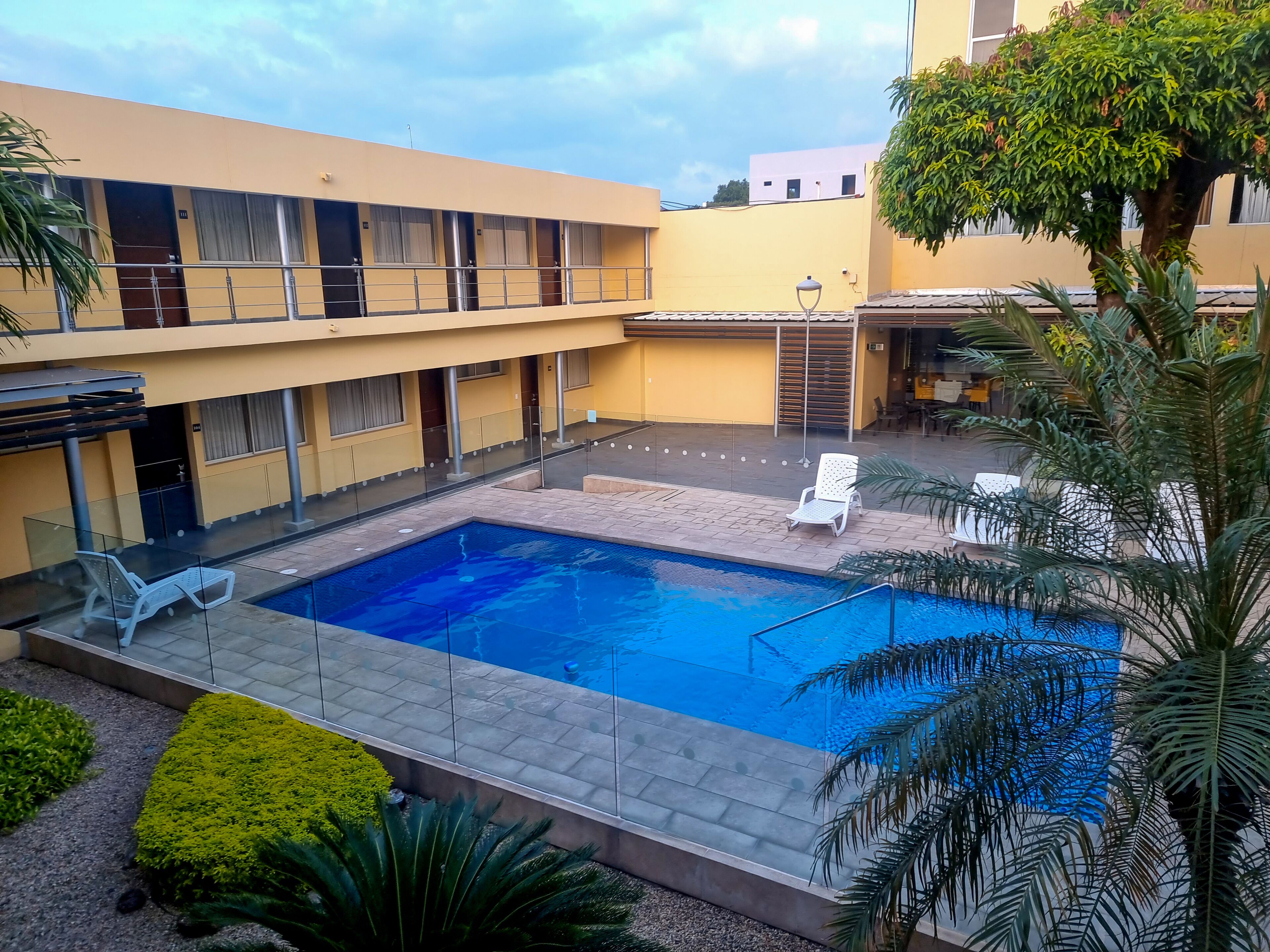 Un patio de hotel con piscina, sillones reclinables y una zona de estar cubierta.