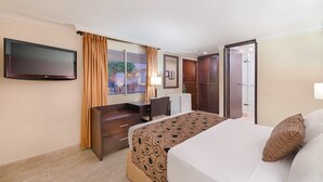 Une chambre d’hôtel avec un lit, un bureau, une télévision, une armoire et une porte de salle de bain.