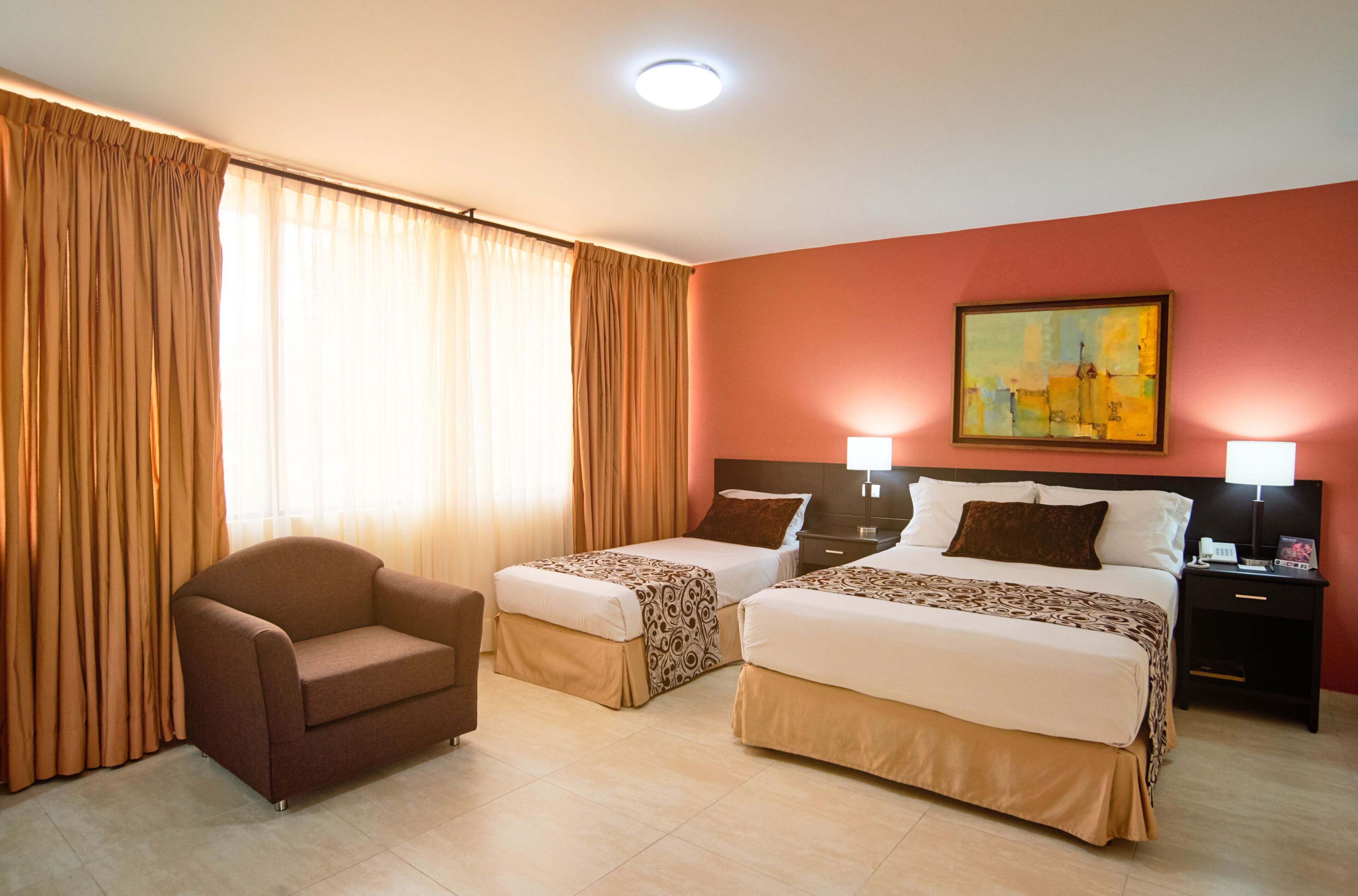 Une chambre d’hôtel avec deux lits, un canapé et un tableau au mur.