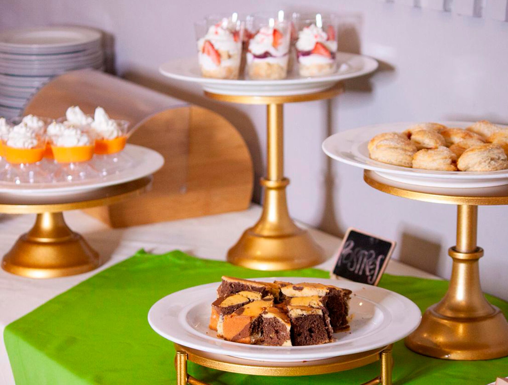 A dessert display with various cakes and pastries on golden stands.