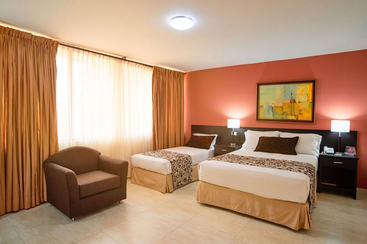 Ein Hotelzimmer mit zwei Betten, einem Sessel und einem Bild an der Wand.