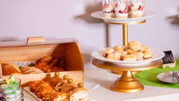 A buffet table with various food items including pastries, sandwiches, and desserts.