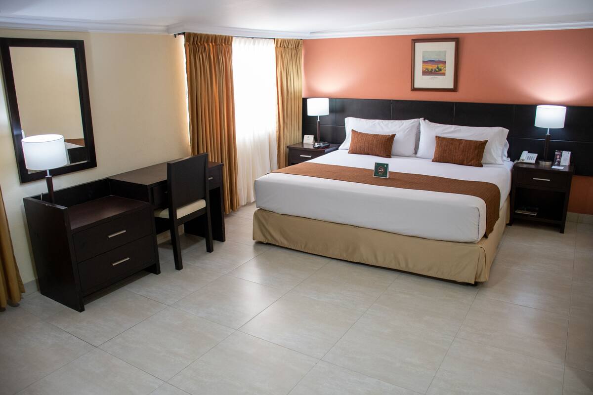 Ein Hotelzimmer mit Bett, Schreibtisch, Stuhl und Nachttischen.
