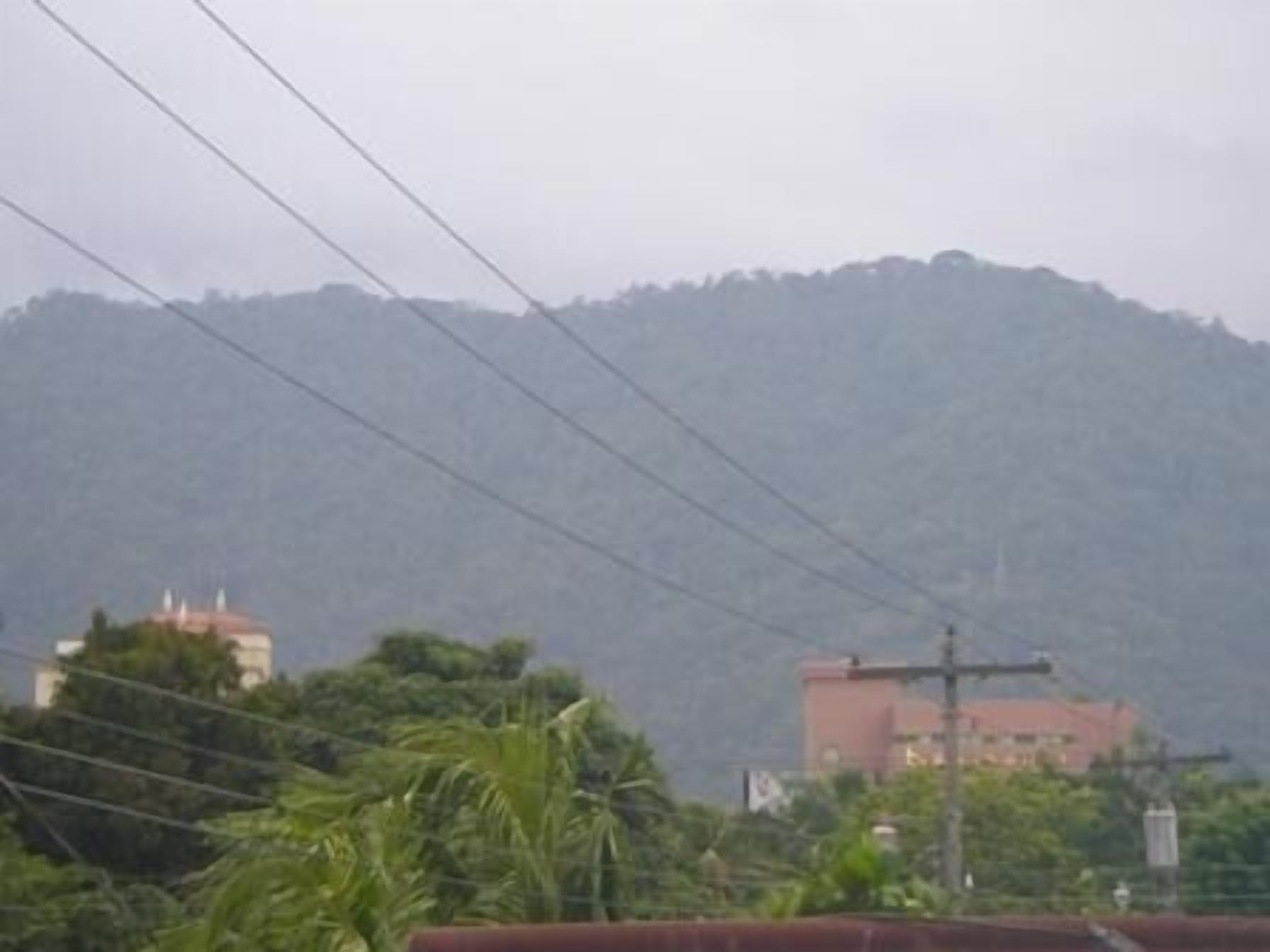 Vista de un paisaje montañoso con edificios y líneas de electricidad.