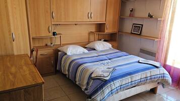 Une chambre à coucher comprenant un lit, une armoire en bois, une table de chevet et un bureau.