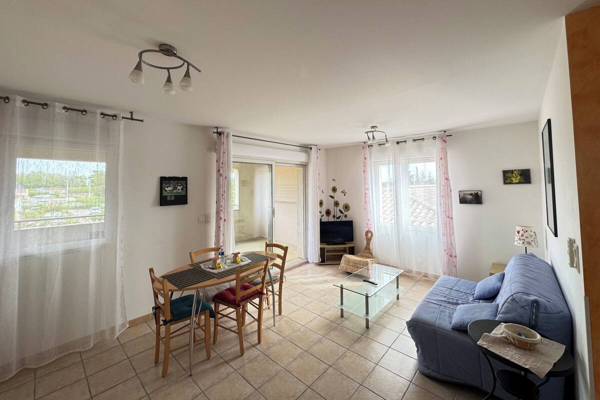 Una sala de estar con comedor, sofá, televisor y balcón.