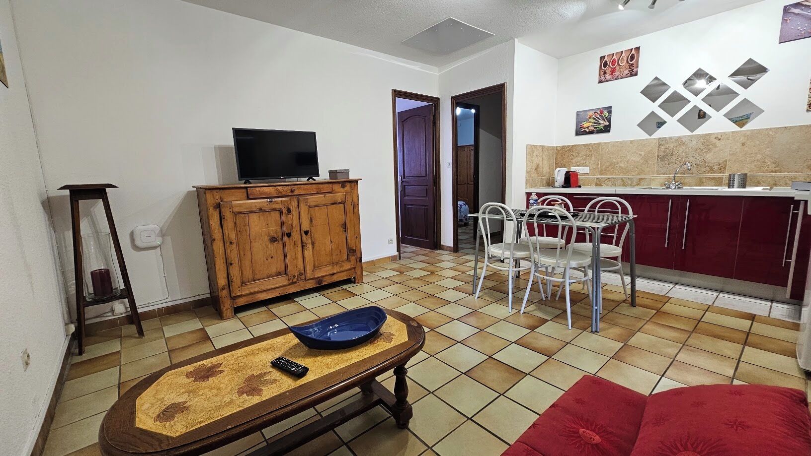 Een woonkamer met een televisie, een houten kast en een eethoek met stoelen en een tafel.