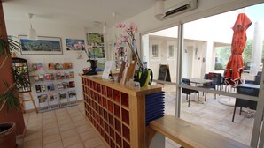 A reception area with a wooden counter, a potted plant, and a view of the outdoor seating area.