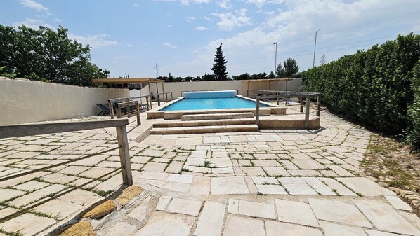 Una piscina al aire libre de temporada, sombrillas
