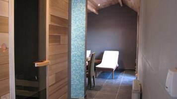 A hallway with wooden walls and a tiled floor, leading to a room with a bed and a chair.