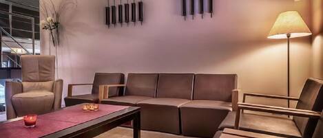 A modern living room with a sofa, armchairs, a coffee table, and a floor lamp.
