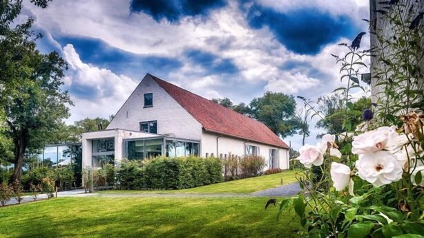 A modern house with a sloped roof, large windows, and a well-maintained lawn.