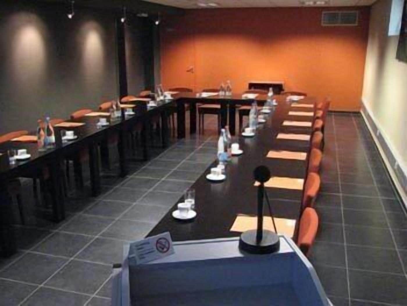 Une salle de conférence avec une longue table, des chaises et un pupitre.