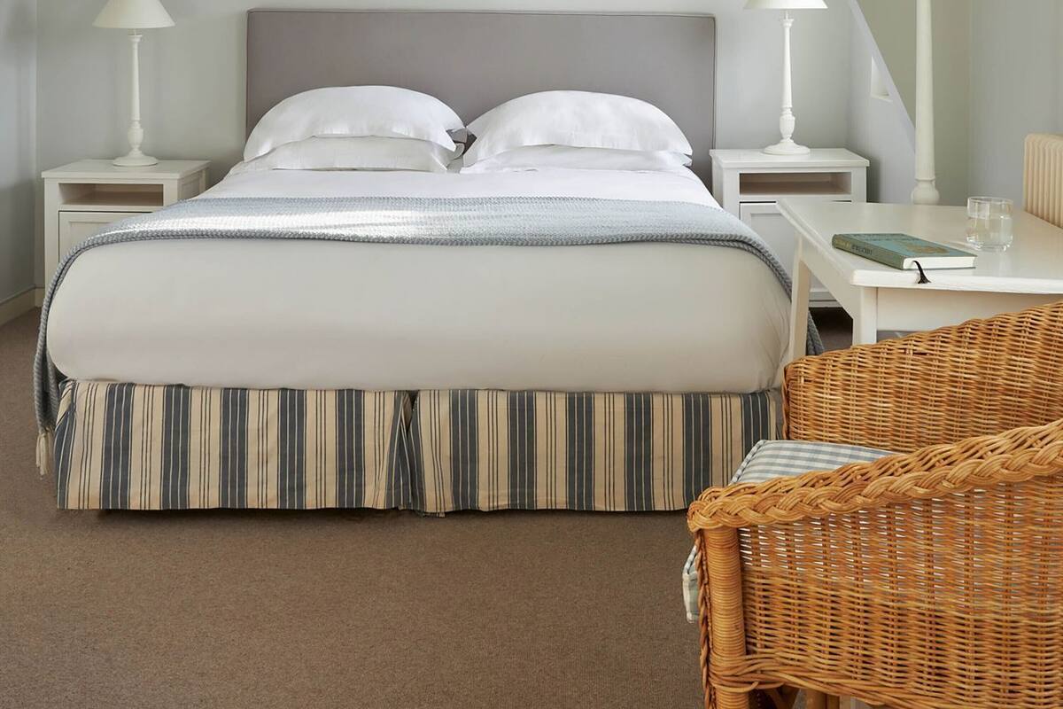 A bedroom with a bed, two bedside tables, a chair, and framed pictures on the wall.