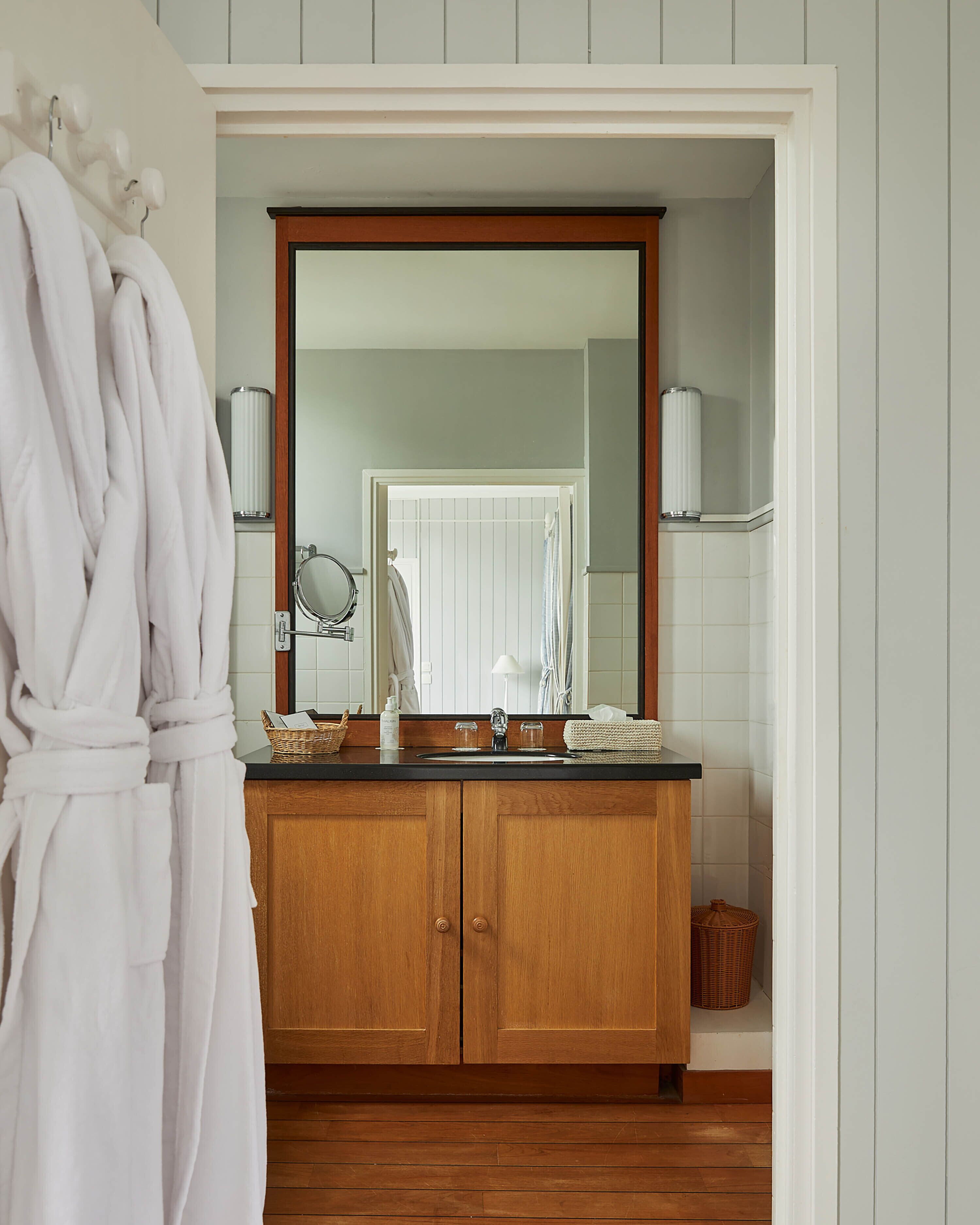 A bathroom with a wooden vanity, a large mirror, and a white bathtub.