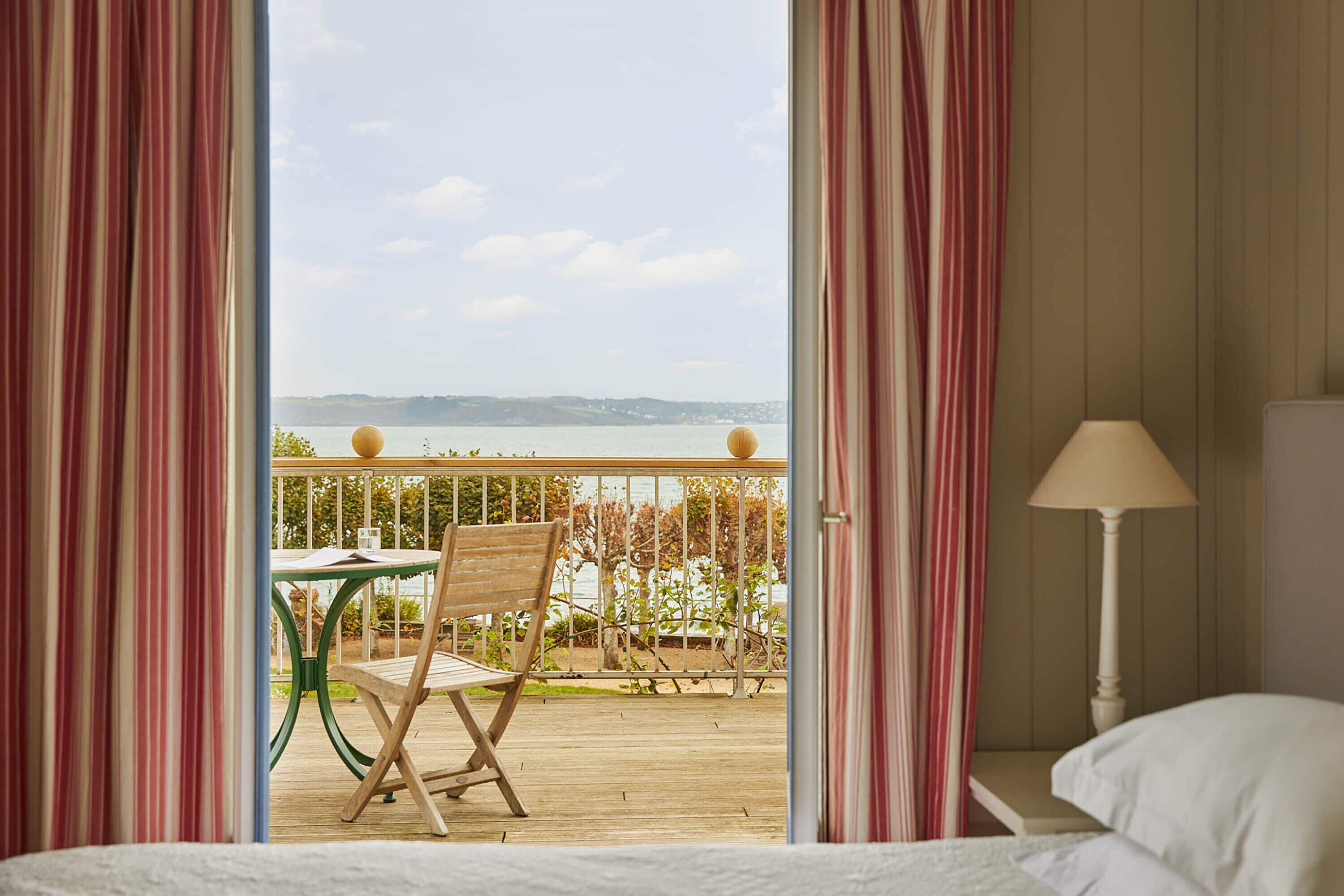 A hotel room with a view of a balcony, a wooden table, and a chair.