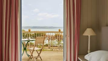 A hotel room with a view of a balcony, a wooden table, and a chair.
