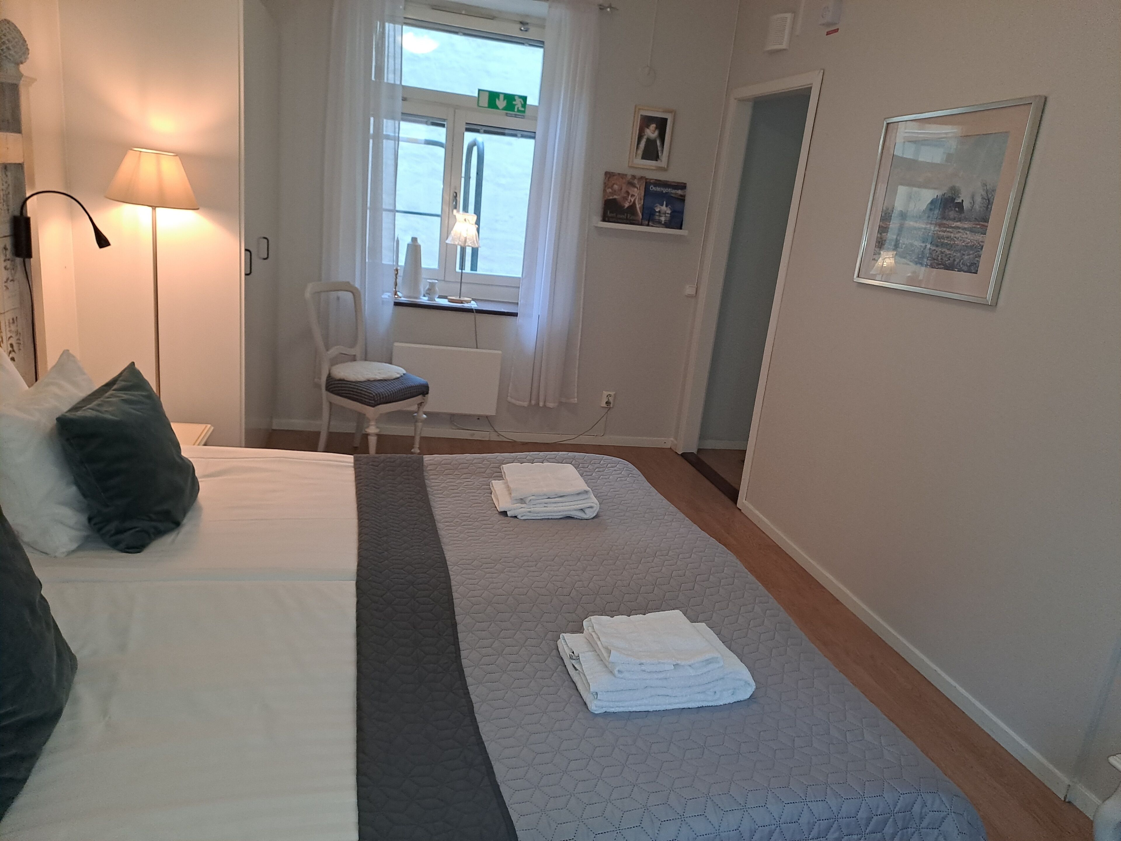 A hotel room with a bed, a chair, a desk, and a window.