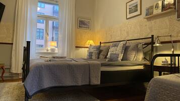 A neatly arranged bedroom with a bed, a bedside table, a lamp, and a window with curtains.