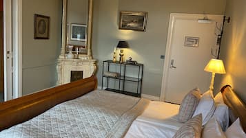 Quarto com uma cama grande, cômoda, espelho e porta.