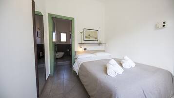 Una habitación de hotel con cama, baño y pasillo.