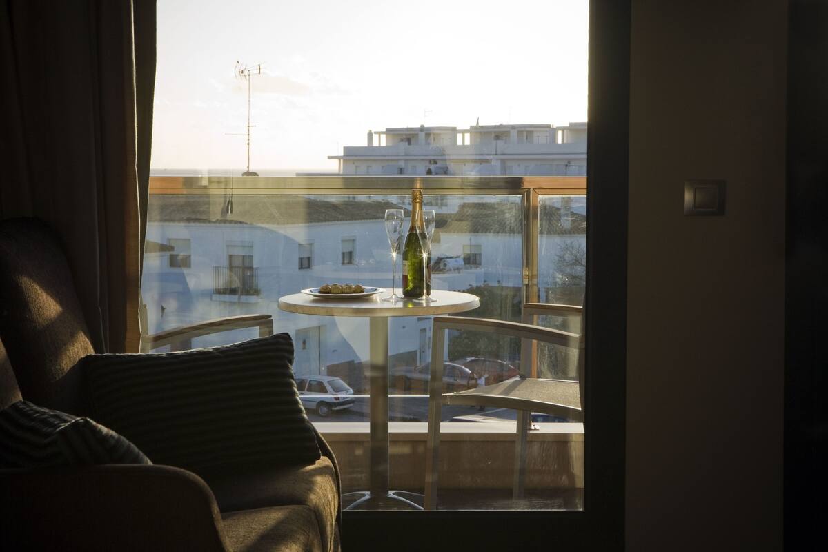 Ein Balkon mit Glastisch, einer Flasche und zwei Gläsern.