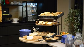 A buffet setup with various breads, pastries, and fruits.