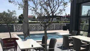 An outdoor patio area with tables and chairs, a small pool, and a decorative tree.