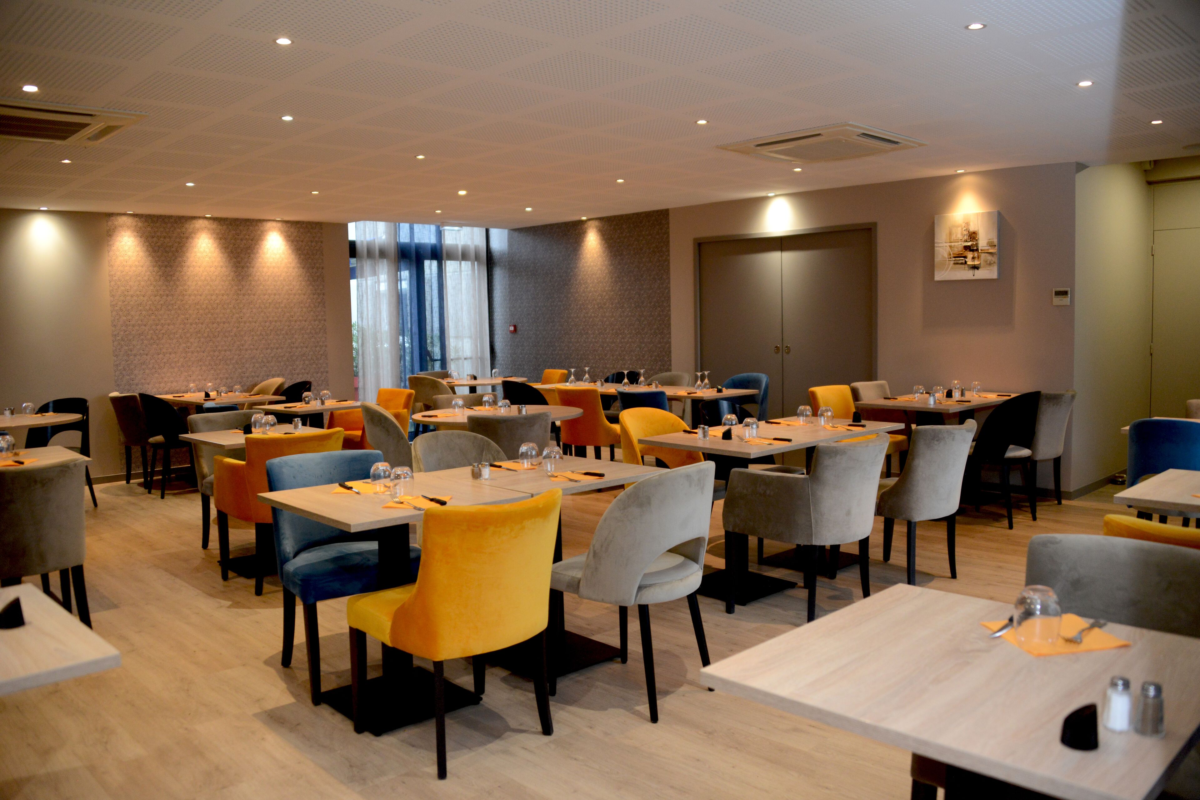 A modern dining area with multiple tables and chairs, featuring a mix of colors and a clean, contemporary design.