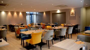 A modern dining area with multiple tables and chairs, featuring a mix of colors and a clean, contemporary design.