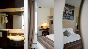 A hotel room with a bed, a desk with a chair, a bathroom with a sink, and a mirror.