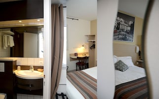 Quarto de hotel com cama, escrivaninha e cadeira, banheiro com pia e espelho.