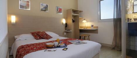 Una habitación de hotel con cama, bandeja de desayuno, mesita de noche y una ventana con cortinas.