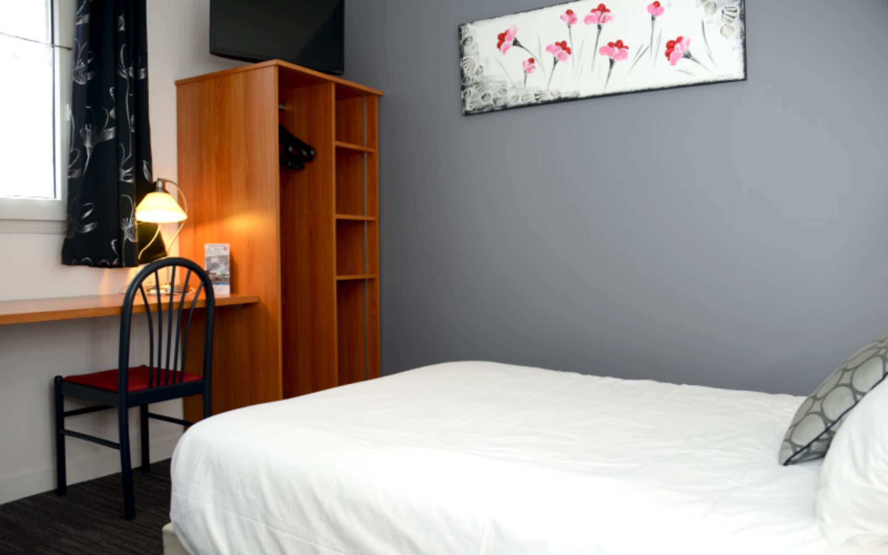 A bedroom with a bed, a desk with a chair, a bookshelf, and a painting on the wall.