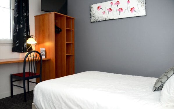 A bedroom with a bed, a desk with a chair, a bookshelf, and a painting on the wall.