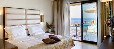 A hotel room with a large bed, a view of the pool, and a balcony with outdoor furniture.