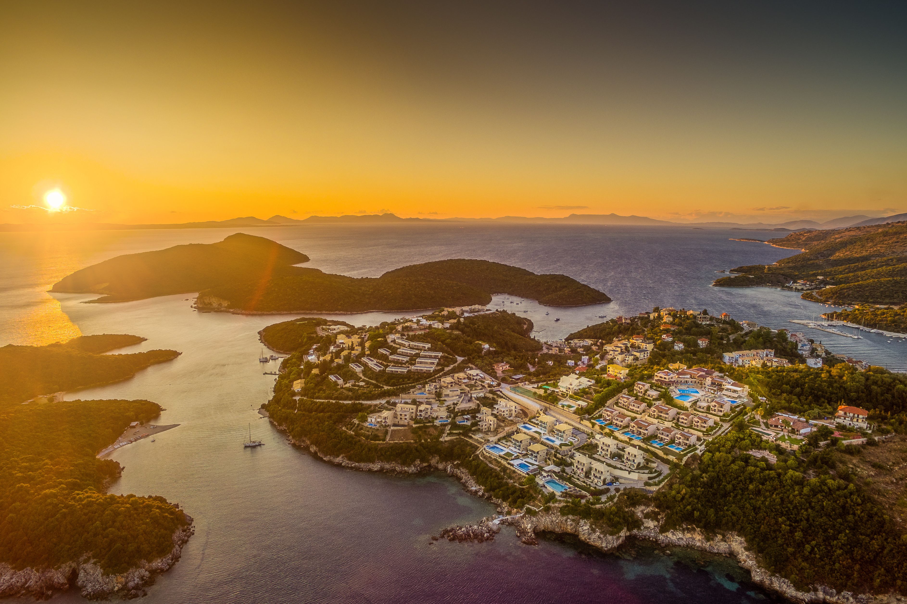 An aerial view of a coastal resort with multiple buildings, a marina, and surrounding water bodies.