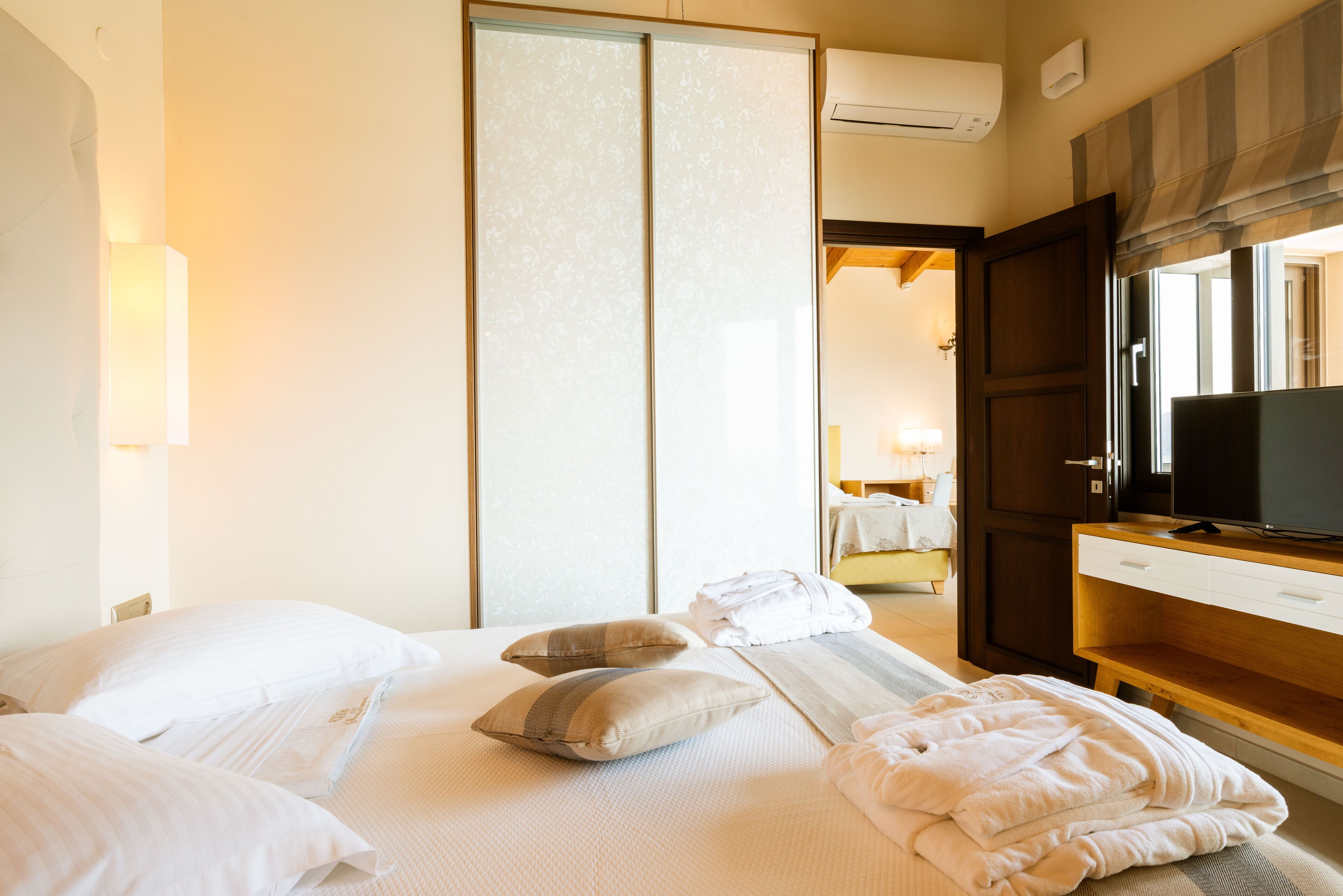 Habitación de hotel con cama, almohadas, televisor y escritorio de madera.